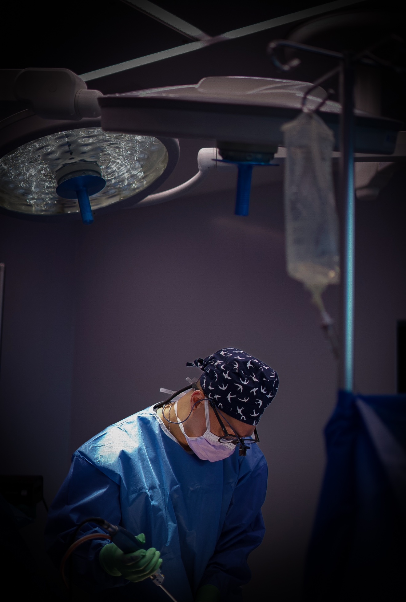 Dr James Lee en pleine opération dans sa salle chirurgicale, blouses et lampes chirurgicales